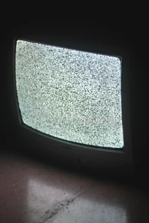 gray crt tv turned on in a dark room